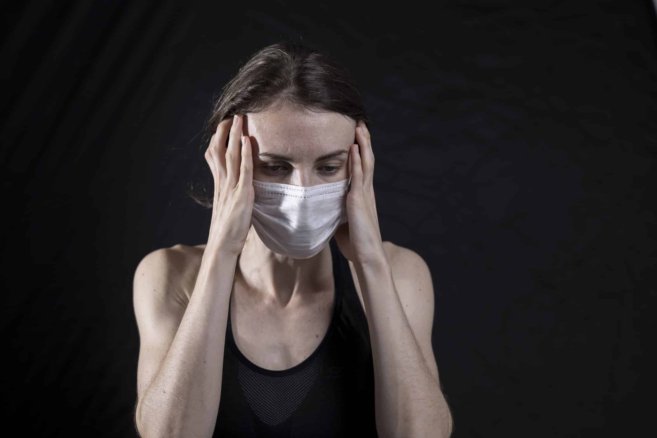 Masked woman touching her temples