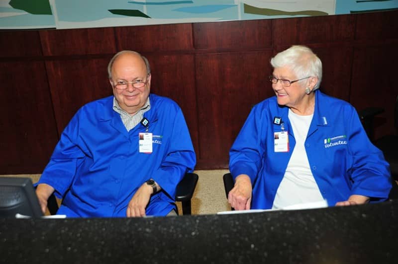 Two volunteers with blue coats sitting.